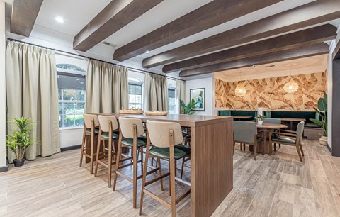 a dining area with chairs and a bar and windows